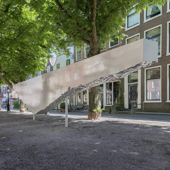 Gecoat EPS-kunstobject met ruwe onderzijde, geplaatst als permanente installatie in een stadsstraat met bomen en historische gevels