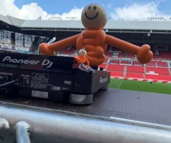 Op het veld in het Phillips stadion staat een paal met een lachend gezichtje er op waaraan twee armen zijn toegevoegd. Deze paal staat achter een DJ tafel en moet de DJ voorstellen.