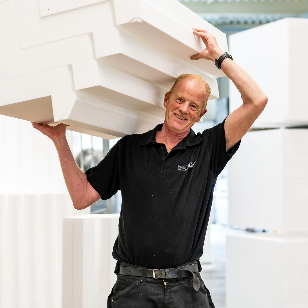 Fred van de Weijenberg draagt een aantal piepschuim (contra)mallen op zijn schouder. Hij draagt onze zwarte bedrijfskleding.