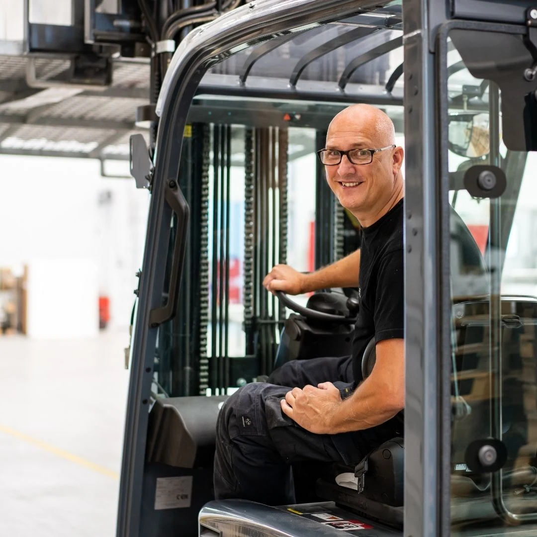 Henny van den Eijnde draagt onze zwarte bedrijfskleding terwijl hij met de heftruck een pallet met tempex blokken vervoert.