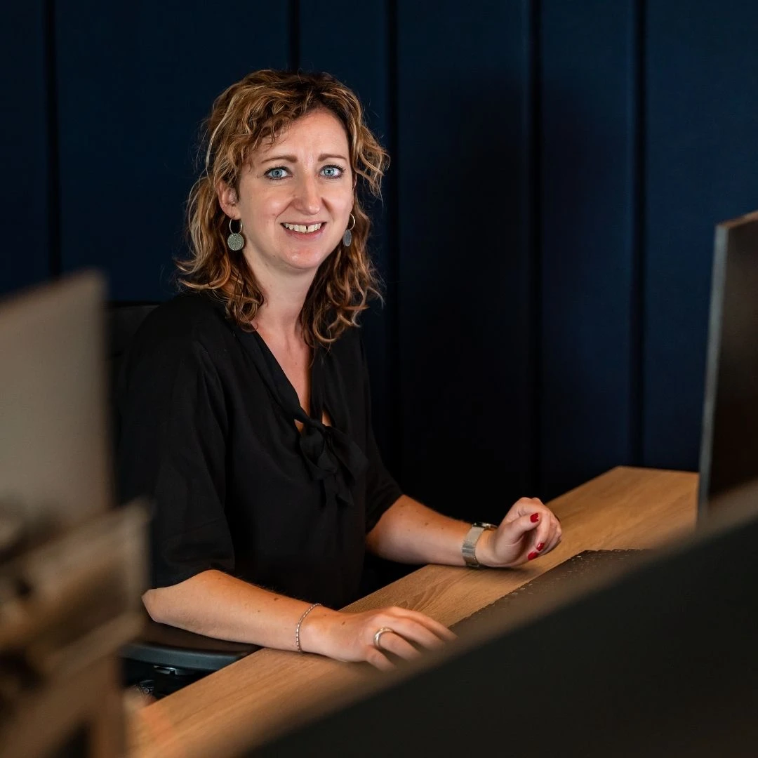 Lieke van Helden - van Lipzig zit, gekleed in een zwarte blouse, aan haar bureau om socialmediaberichten te plaatsen over de kunstwerken, bouwelementen en verpakkingen die wij van EPS maken.