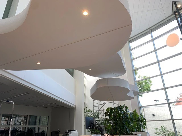 Boven de balie in het gemeentehuis van Baarn hangt een wolkendek van contourgesneden piepschuim waarin spotjes zijn verwerkt.